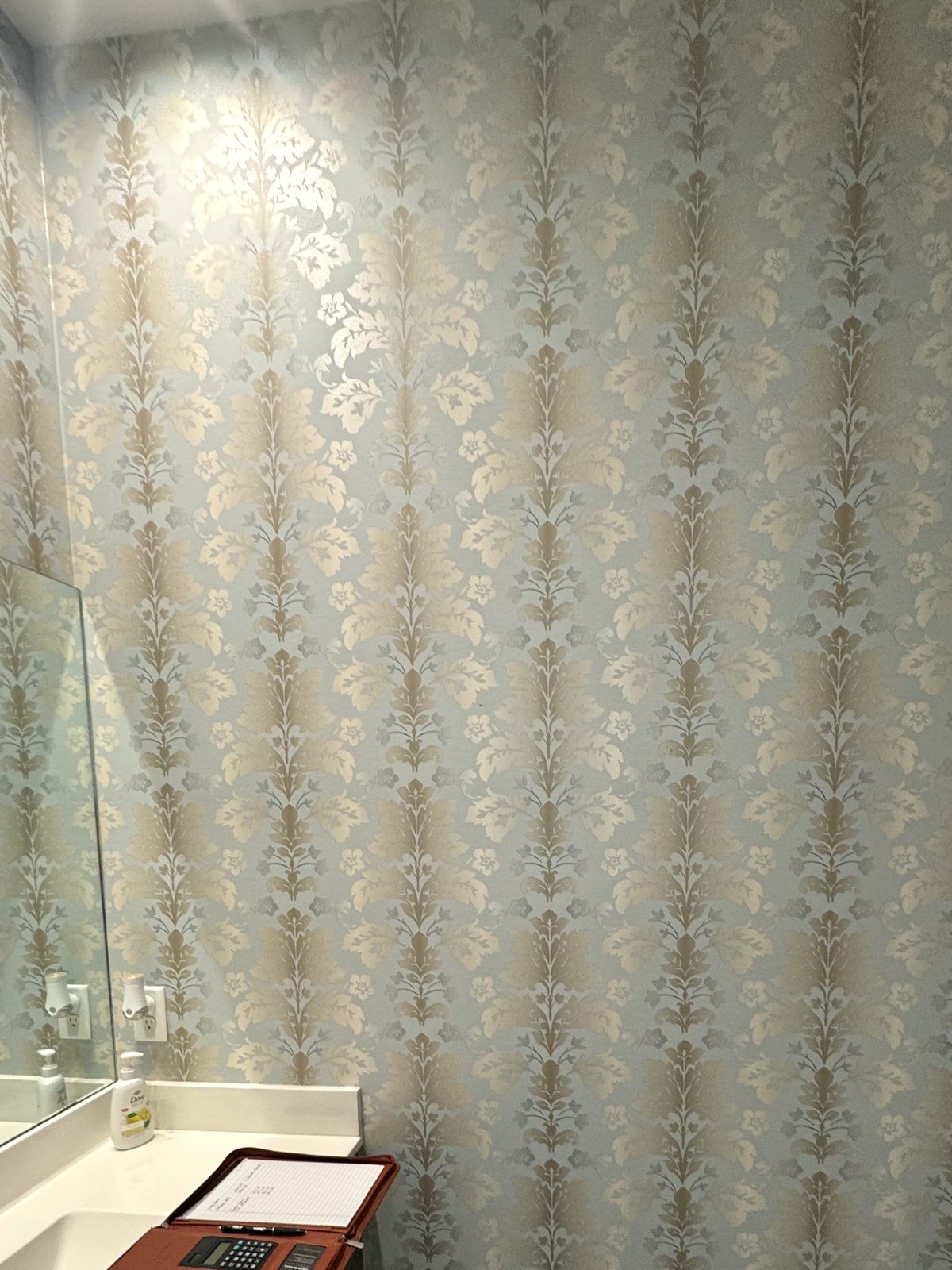 Metallic damask, powder room. A mica ground that changes with the light, hung so the sheen runs unbroken from corner to corner.