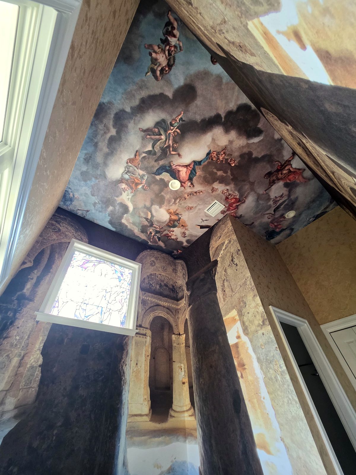 Baroque sky mural, vaulted ceiling. A single mural carried across four ceiling planes and down the walls, with the arches meeting at the corners.